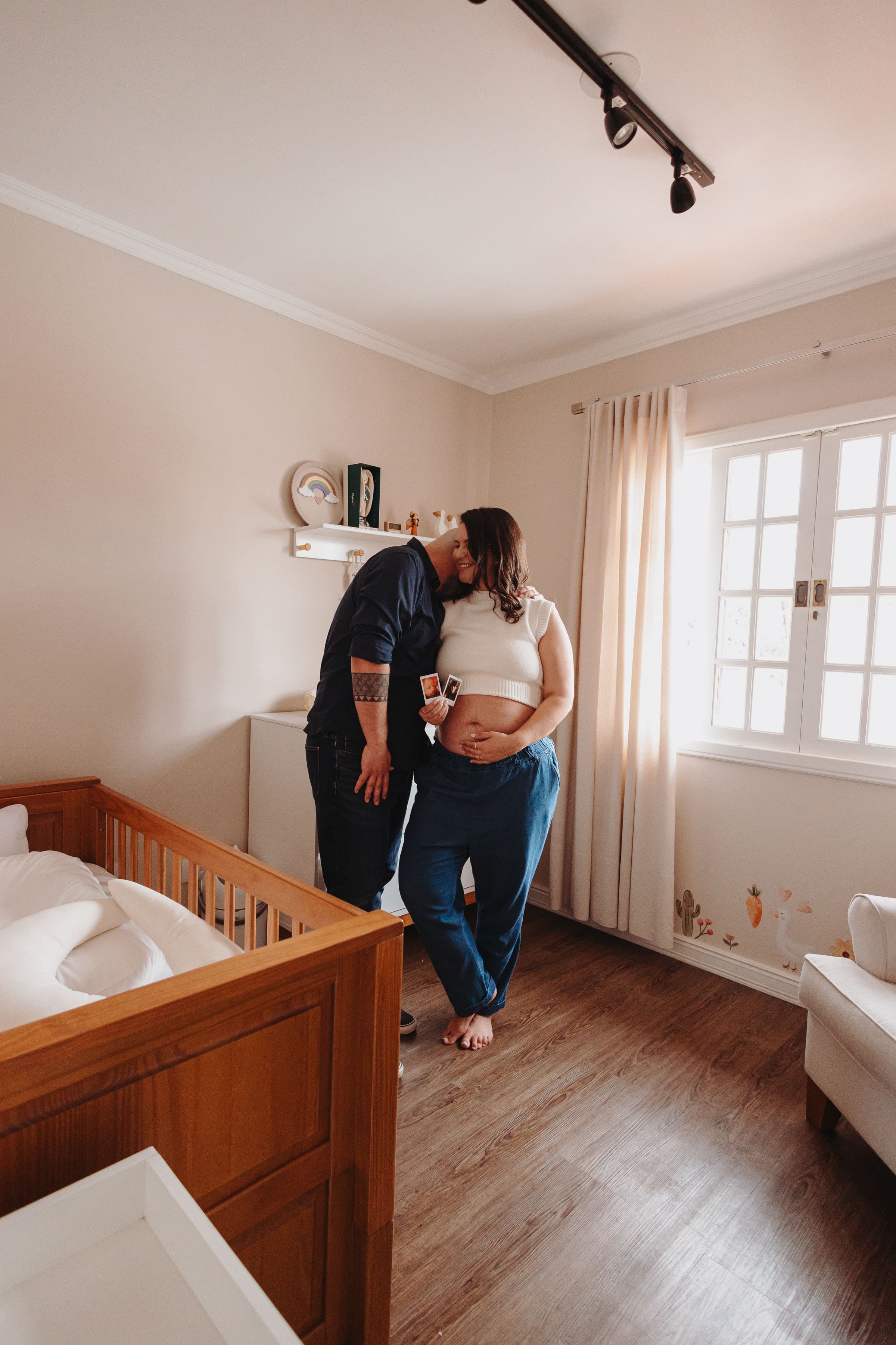 Casal na sala do bebê com o ultrassom na mão