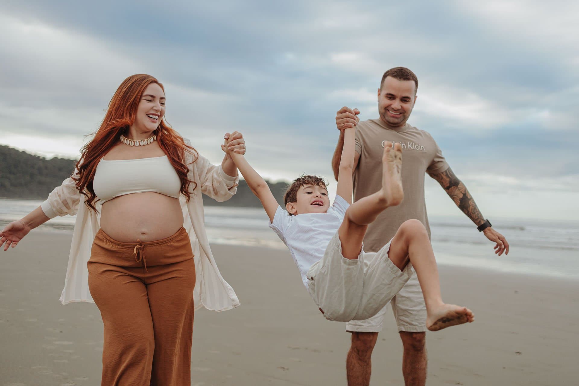 Família correndo de mãos dadas na praia