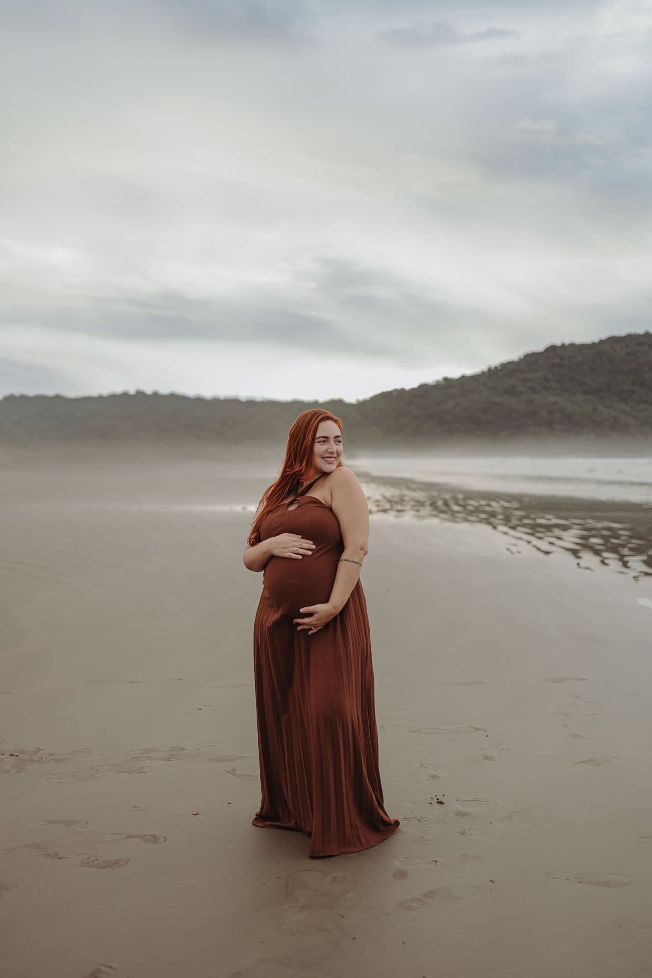 Gestante de vestido longo na praia