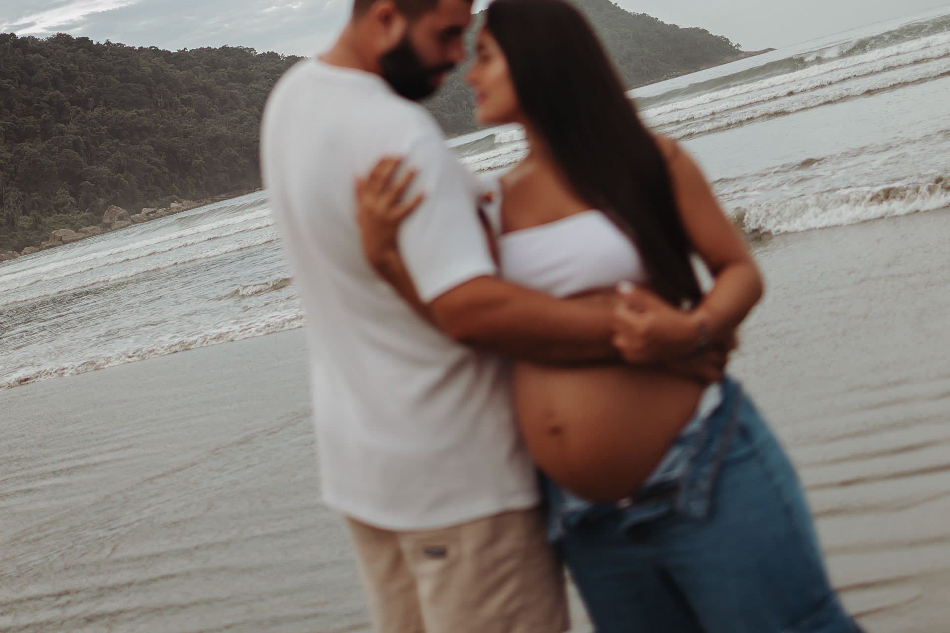 Abraço do casal na praia, com a barriga à mostra